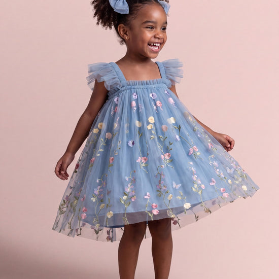 Girl wearing the Aurora Dress in dusty blue embroidered floral tulle, front
