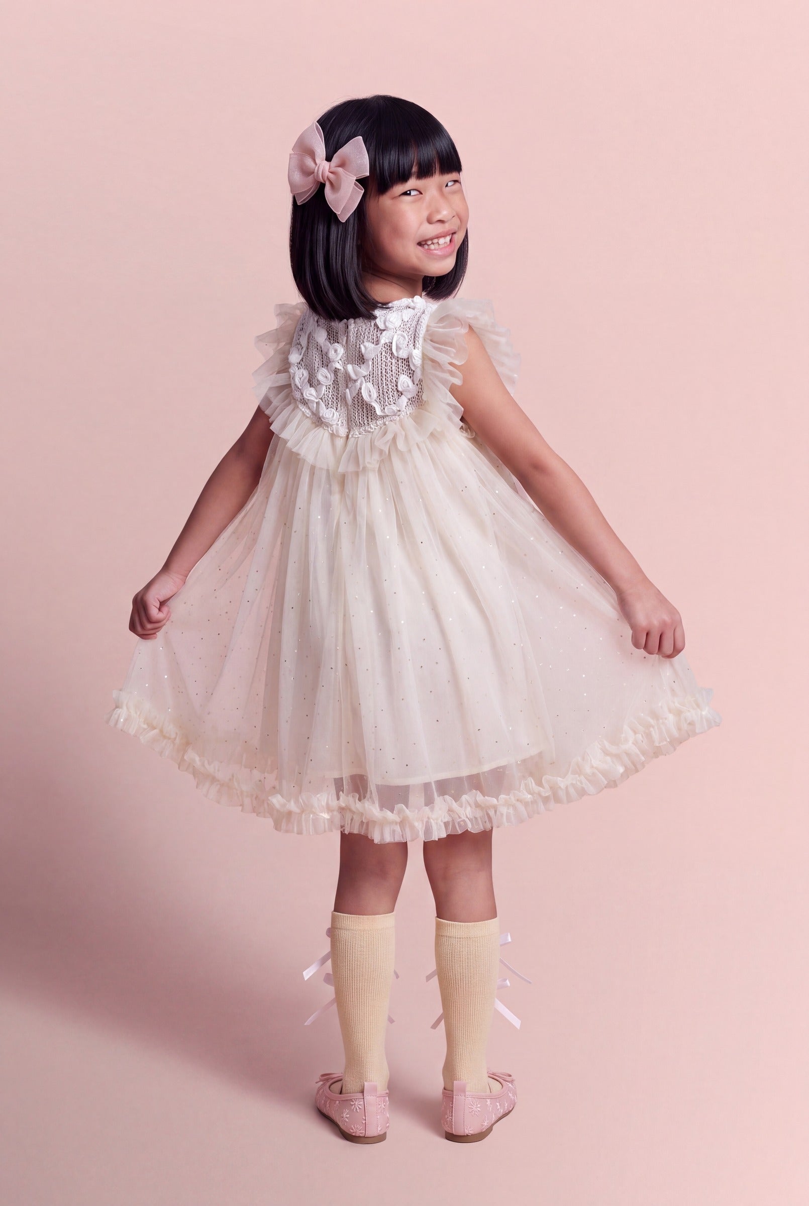 Back view of the Primrose ivory dress, the crochet yoke carrying its gauze roses across the shoulders