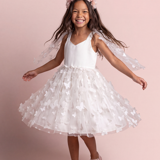 Blossom white butterfly party dress, front view on a girl mid twirl, satin sweetheart bodice and tulle skirt covered in 3D fabric butterflies