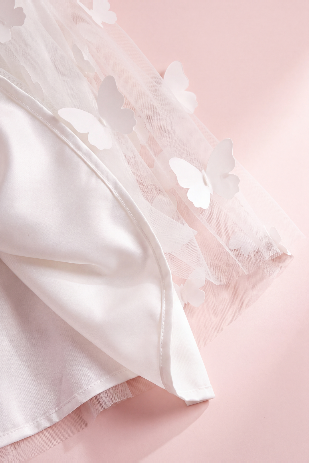 Close up of the Blossom white dress hem, sheer butterfly tulle over the satin lining
