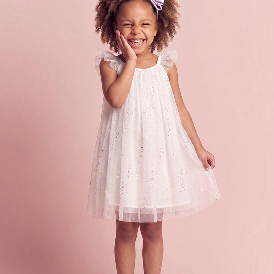 Girl wearing the Bluebell Star Dress in white star tulle, front
