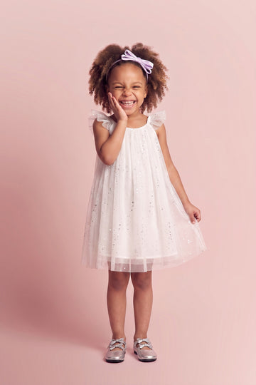 Girl wearing the Bluebell Star Dress in white star tulle, front