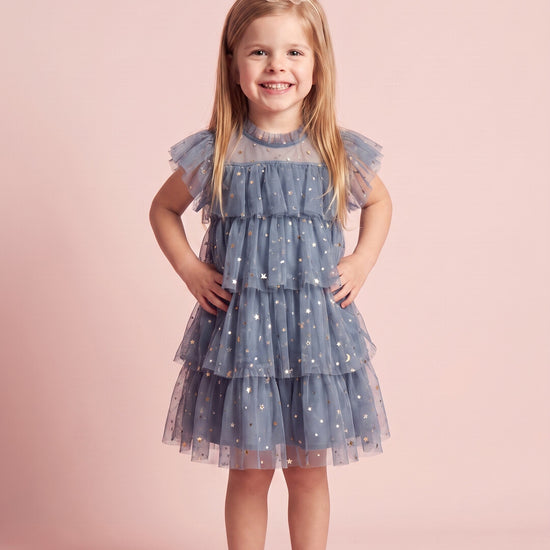 Girl wearing the Celeste Dress in dusty blue star and moon tulle, front