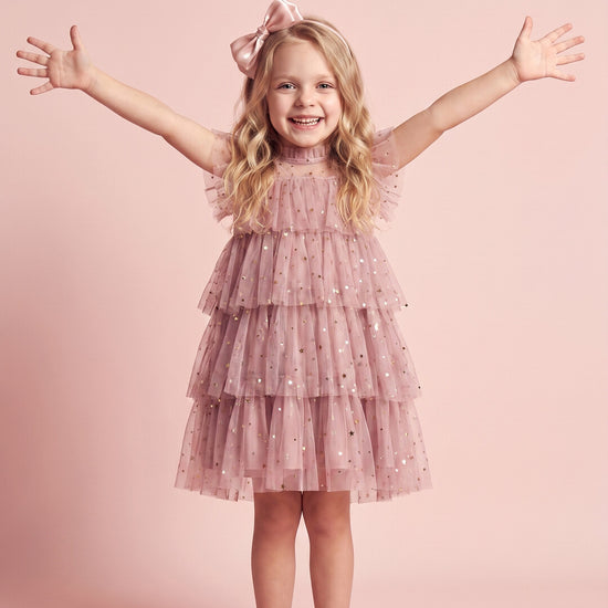 Girl wearing the Celeste Dress in dusty pink star and moon tulle, front