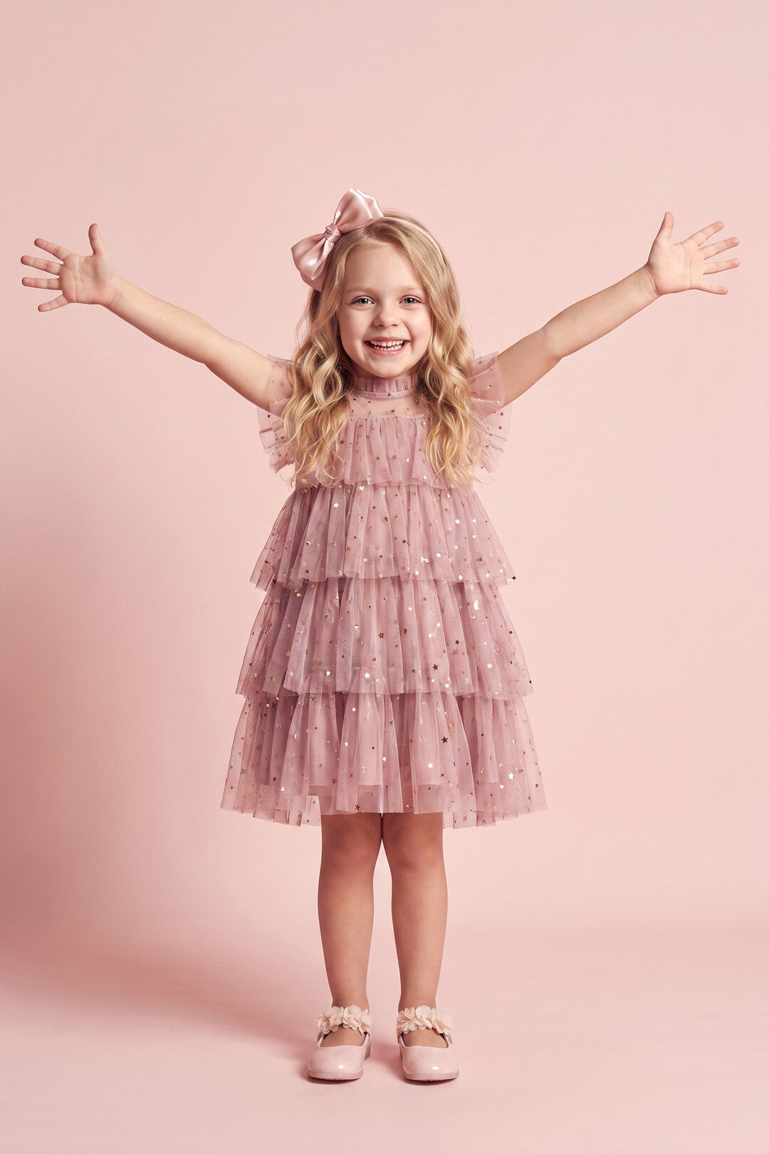 Girl wearing the Celeste Dress in dusty pink star and moon tulle, front
