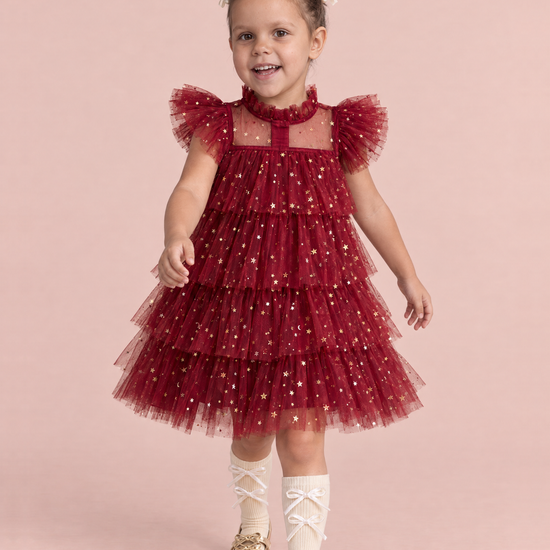 Girl wearing the Celeste Wine Red Flower Girl Dress, front, walking toward the camera with a big smile