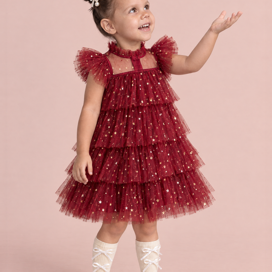 Celeste Wine Red Flower Girl Dress, three quarter view, reaching up to catch a snowflake