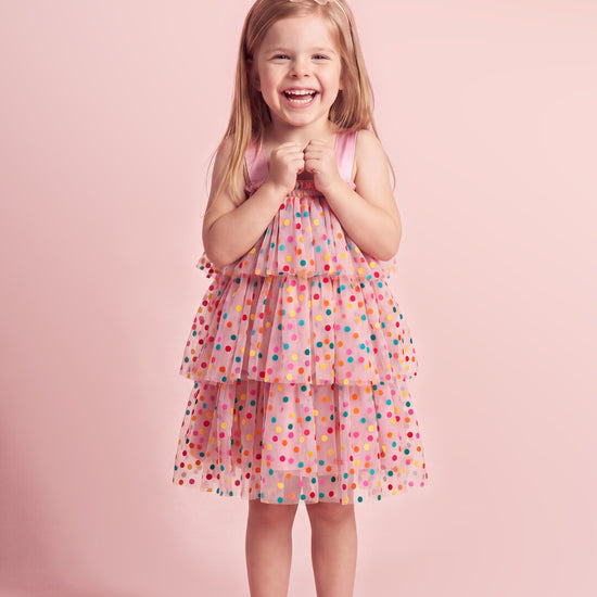 Girl wearing the Confetti Dot Dress in pink with multicoloured dots, front