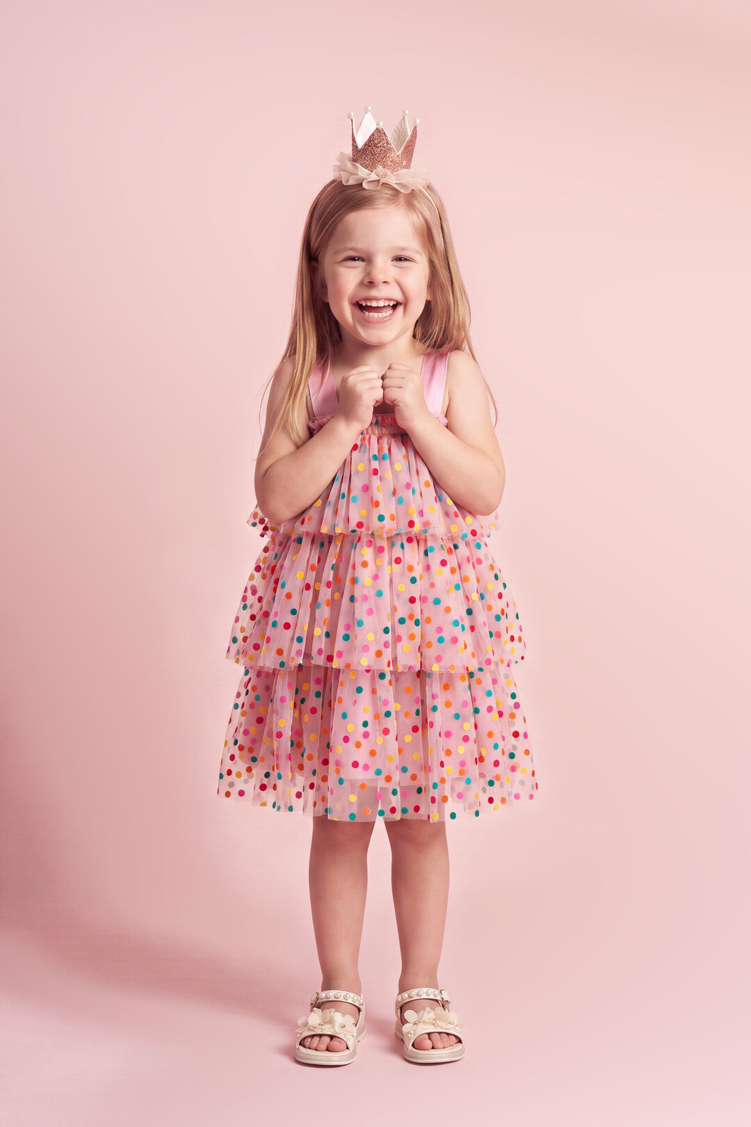 Girl wearing the Confetti Dot Dress in pink with multicoloured dots, front