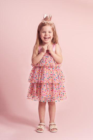 Girl wearing the Confetti Dot Dress in pink with multicoloured dots, front