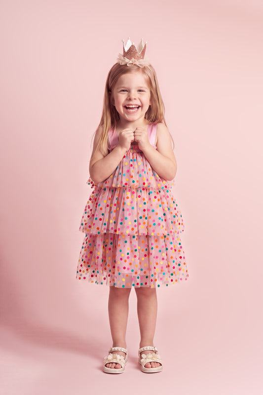 Girl wearing the Confetti Dot Dress in pink with multicoloured dots, front