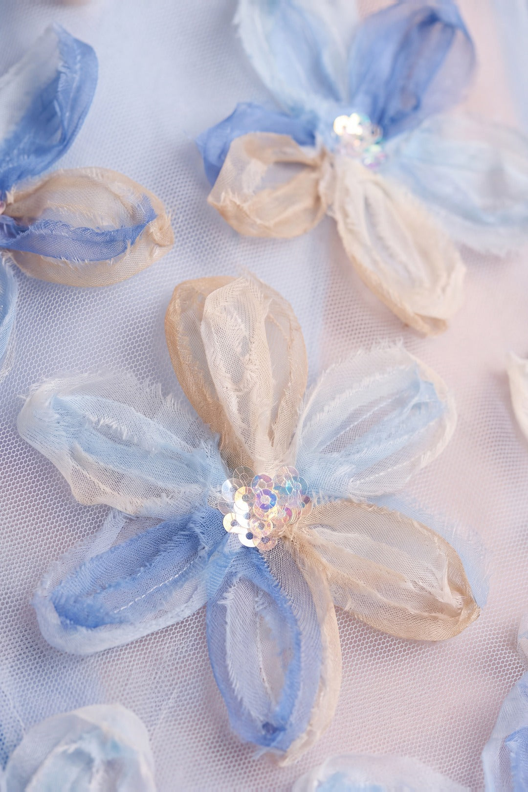 Close up of the applique organza flowers with sequin centres on pale blue mesh