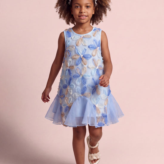 Girl wearing the Cornflower Dress in pale blue mesh with applique flowers, front