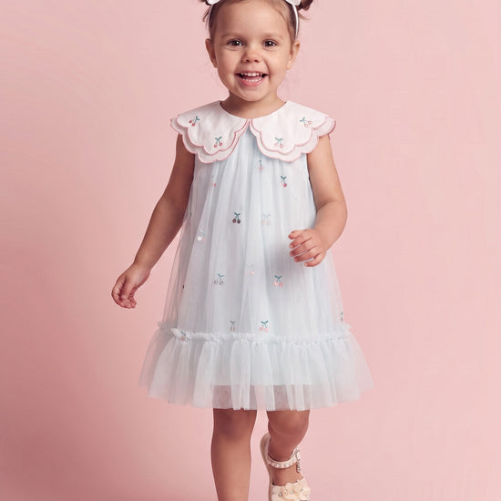 Girl wearing the Forget Me Not Dress in powder blue with cherry collar, front