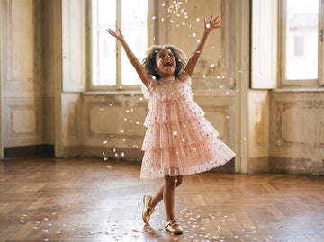 Girl in a pink star tulle party dress throwing confetti in the air