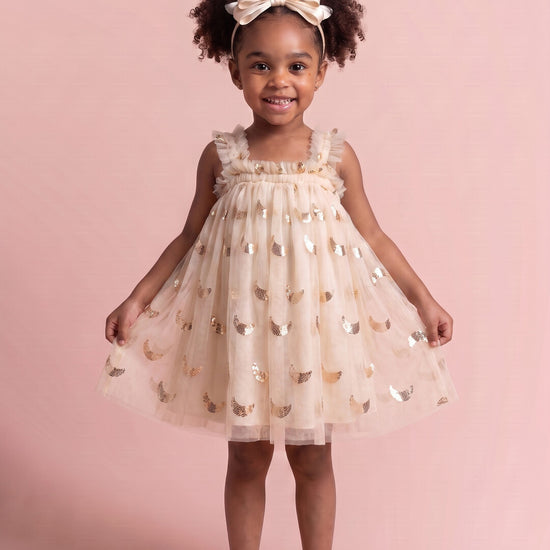 Girl wearing the Midnight Star Dress in cream with gold stars and moons, front