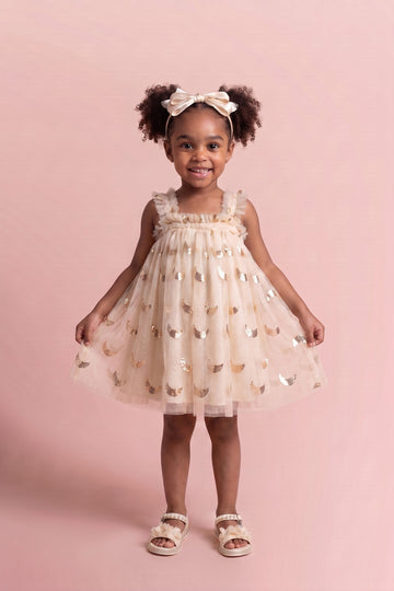 Girl wearing the Midnight Star Dress in cream with gold stars and moons, front