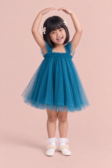 Girl wearing the Papillon Teal Butterfly Back Flower Girl Dress, front, arms curved up overhead like a ballerina