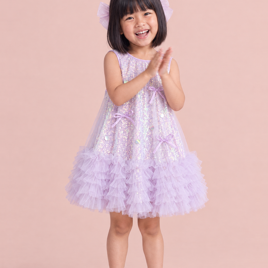 Periwinkle Lavender Sequin Party Dress, front: a girl clapping and laughing in the lavender sequin dress with a ruffle hem