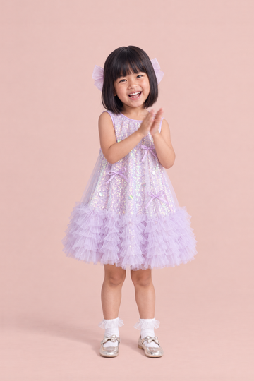 Periwinkle Lavender Sequin Party Dress, front: a girl clapping and laughing in the lavender sequin dress with a ruffle hem