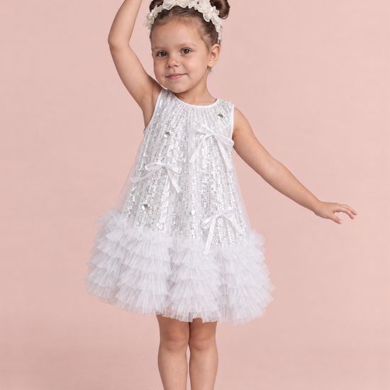 Periwinkle Silver Sequin Party Dress, front: a girl dancing in the white and silver sequin dress with a ruffle hem