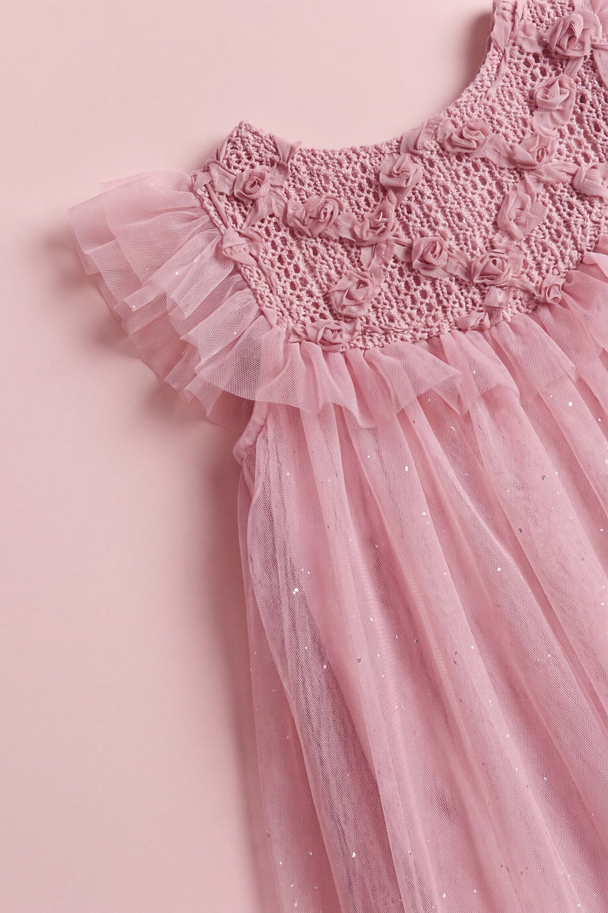 The Primrose pink dress laid flat, showing the crochet yoke and full tulle skirt
