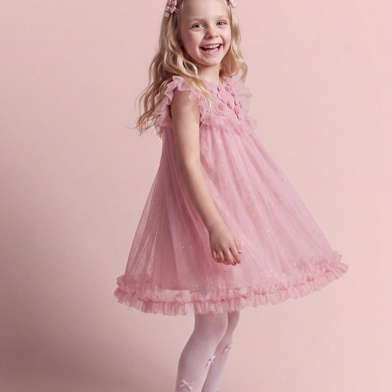 Primrose pink flower girl dress seen at three quarter angle, full tulle skirt in motion