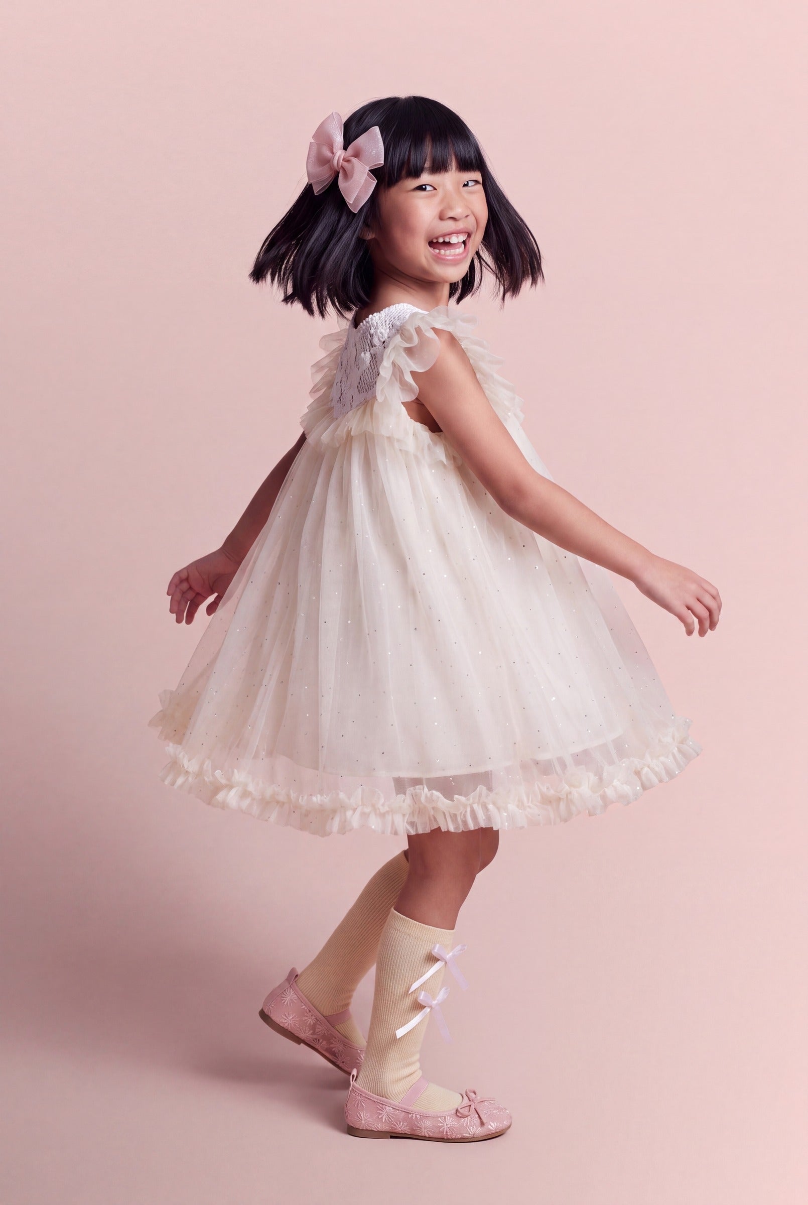 Side view of the Primrose ivory dress mid twirl, the tulle skirt flaring into a full bell