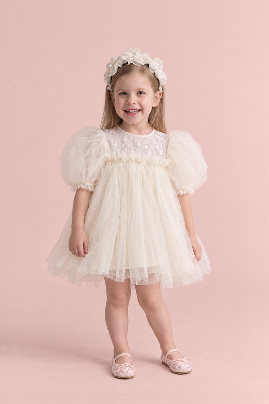 Snowdrop Ivory Puff Sleeve Party Dress, front view on a smiling girl, embroidered tulle yoke, elbow length puffed sleeves and a pearl blossom headband
