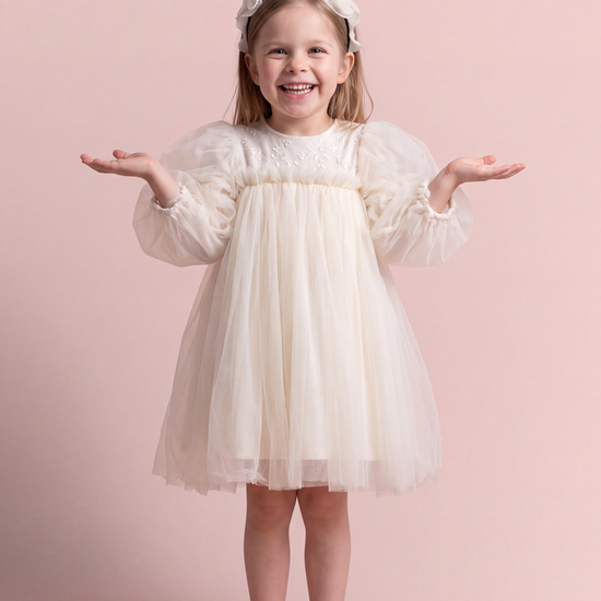 Snowdrop ivory puff sleeve party dress, front view on a girl laughing, embroidered tulle yoke and big puffed sleeves