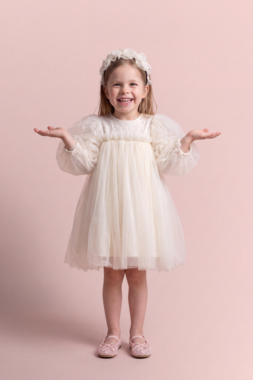 Snowdrop ivory puff sleeve party dress, front view on a girl laughing, embroidered tulle yoke and big puffed sleeves