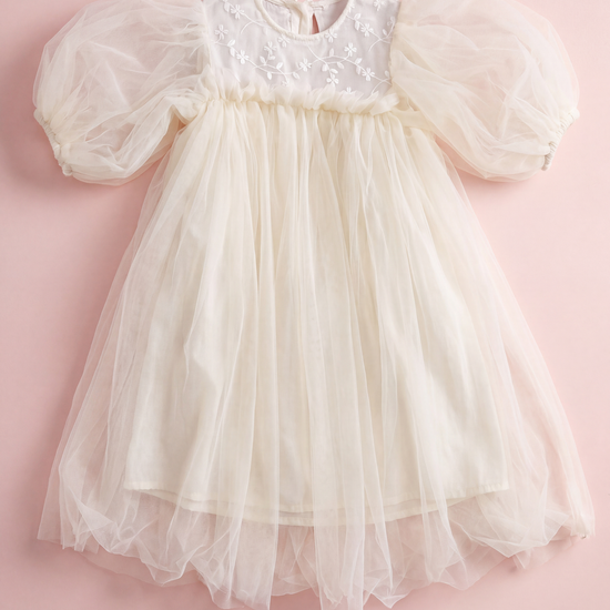 Snowdrop ivory dress laid flat, showing the shallow embroidered yoke, puffed sleeves and layered tulle skirt