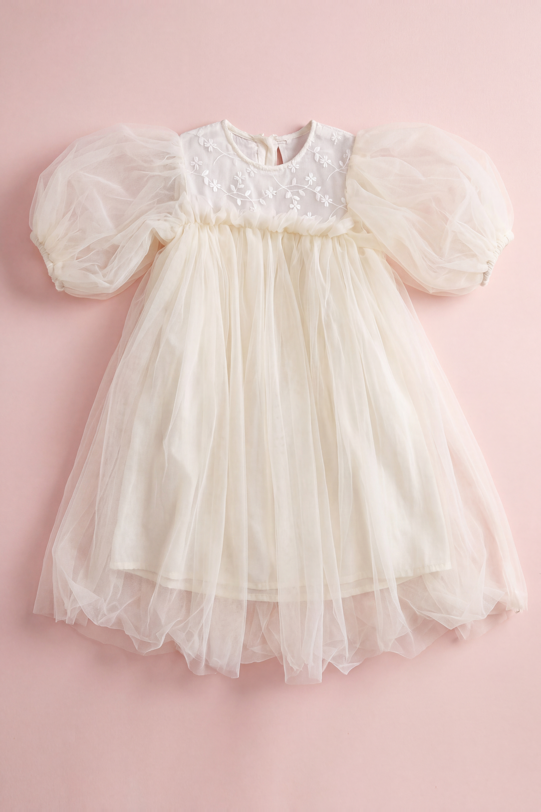 Snowdrop ivory dress laid flat, showing the shallow embroidered yoke, puffed sleeves and layered tulle skirt