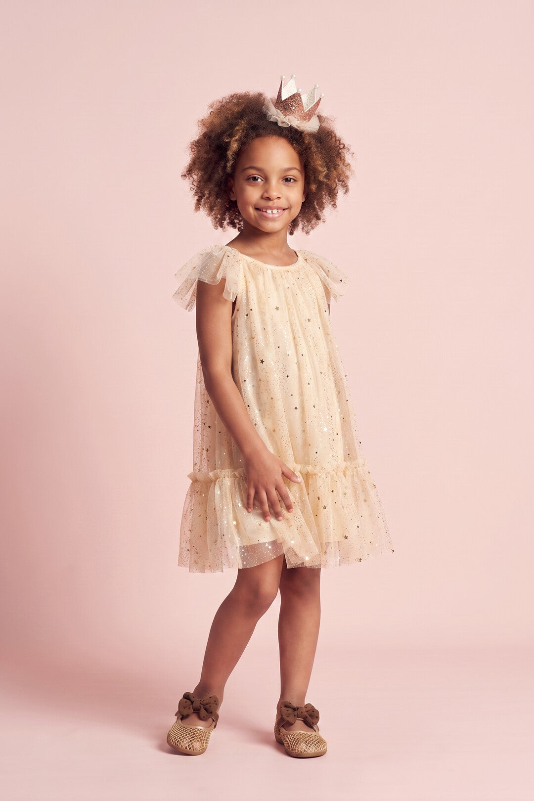 Girl wearing the Starlight Dress in cream gold star tulle, front