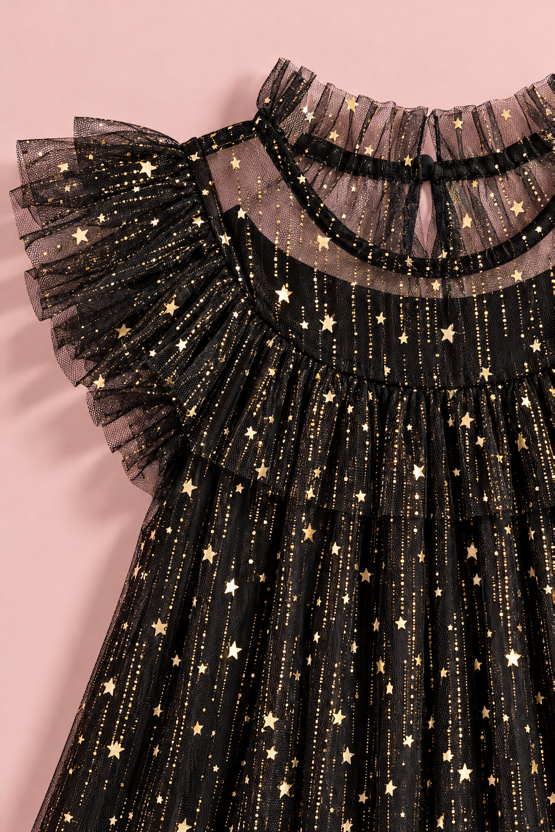 Close up of the gold foil stars and glitter on the black tulle, the ruffle collar and the flutter sleeve