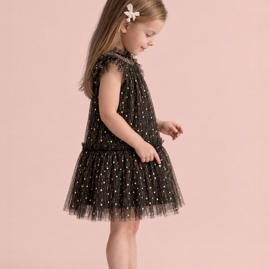 Stardust Black Star Tulle Party Dress, side view, counting the gold stars on her skirt, showing the flutter sleeve and the tulle skirt