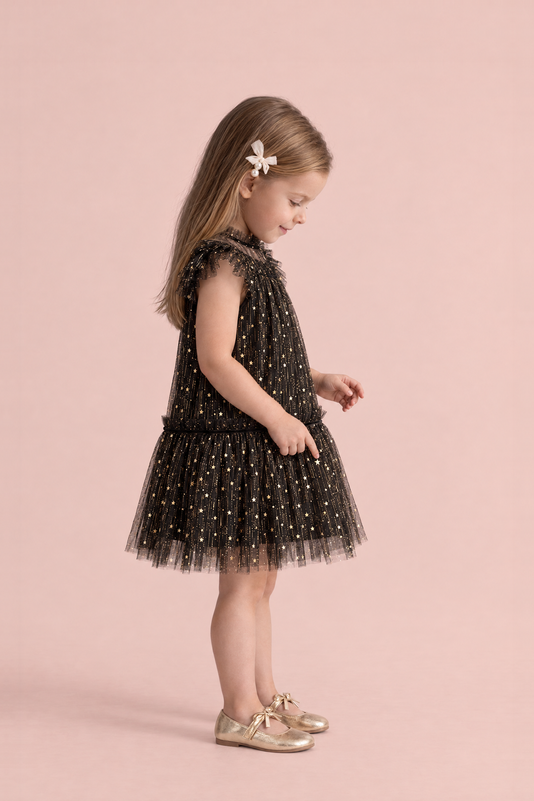 Stardust Black Star Tulle Party Dress, side view, counting the gold stars on her skirt, showing the flutter sleeve and the tulle skirt