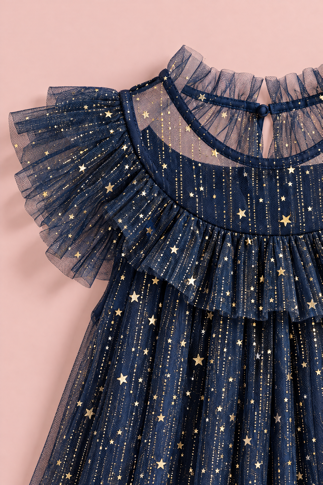 Close up of the gold foil stars and glitter on the navy tulle, the ruffle collar and the flutter sleeve