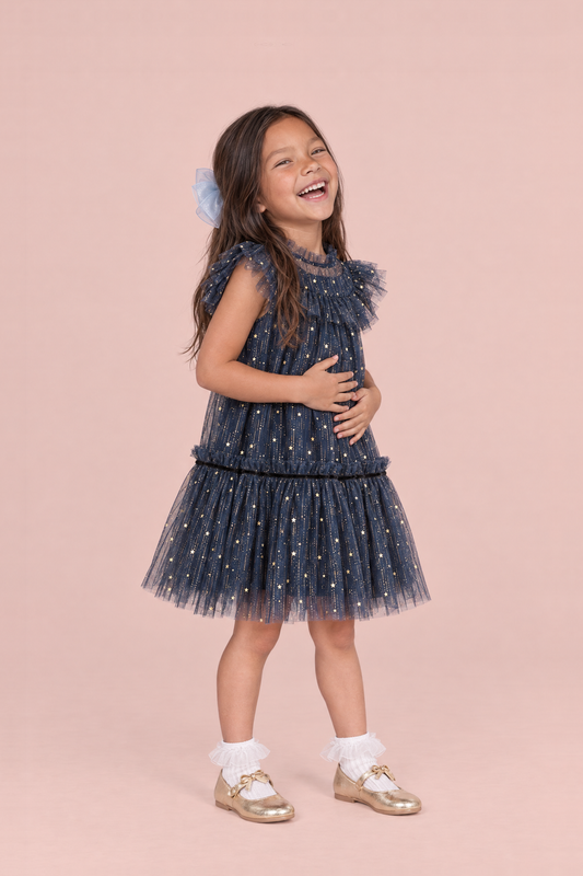 Stardust Navy Star Tulle Party Dress, three quarter view, laughing with her hands on her tummy, showing the ruffle collar and drop waist skirt