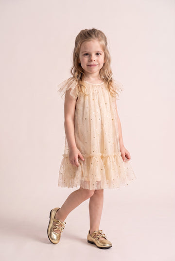 Girl wearing the Starlight Dress in cream gold star tulle, front